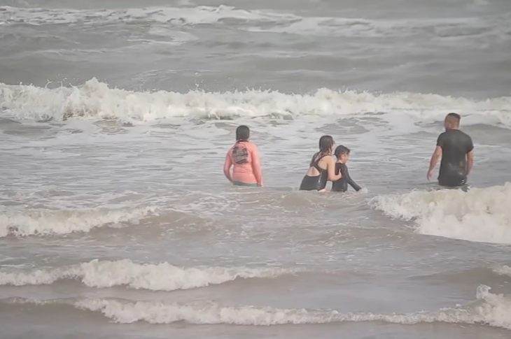 photograph of people swiming in Galveston beach.